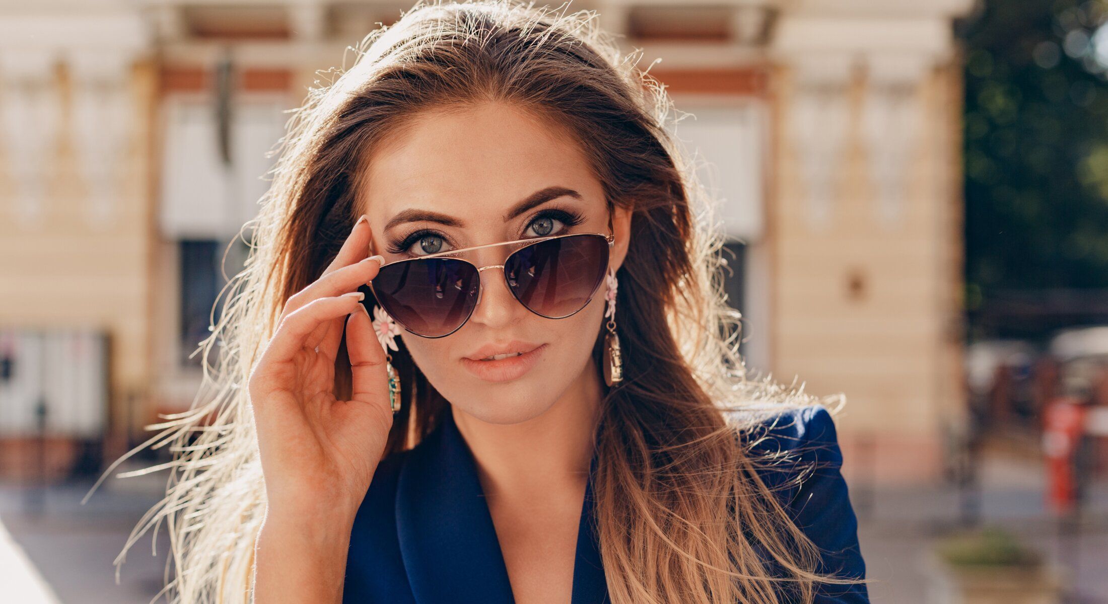 Woman adjusting sunglasses in outdoor setting.